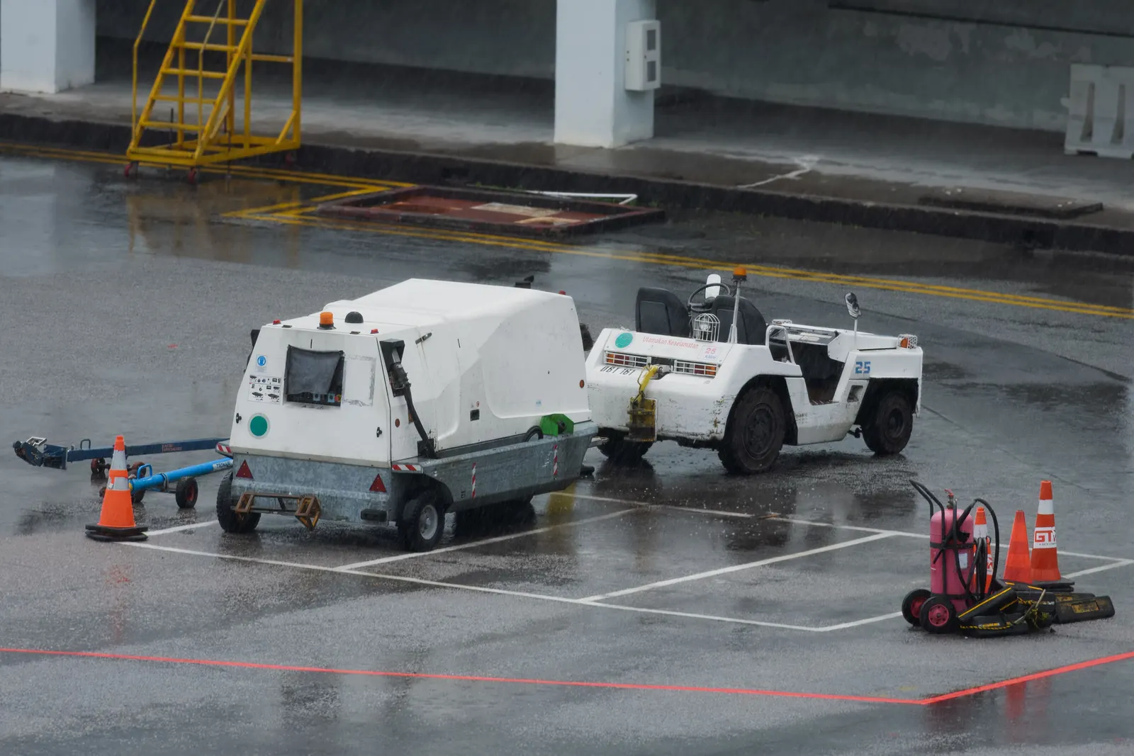 Ground support equipment and a baggage tractor parked on a wet airport apron