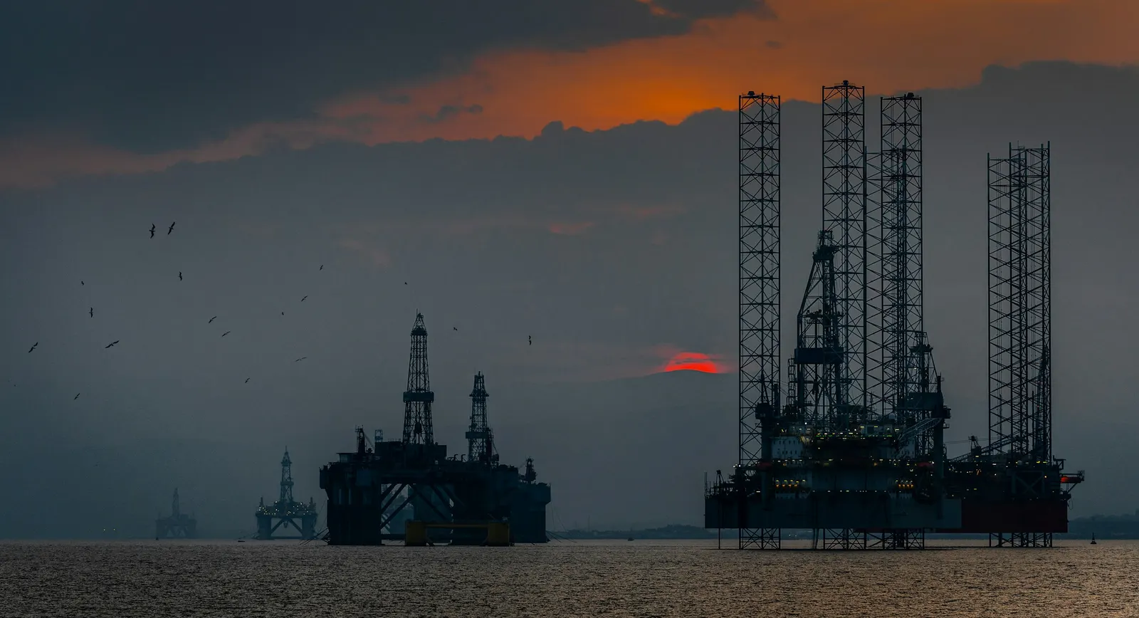 Offshore drilling platforms and jack-up rig at dusk